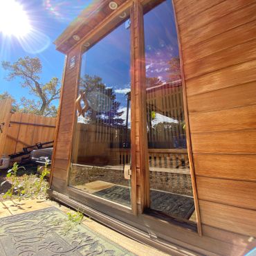 Wooden door with glass reflecting the sky and trees.