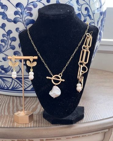 Elegant gold and pearl jewelry set with necklace, bracelet, and leaf-themed earrings.