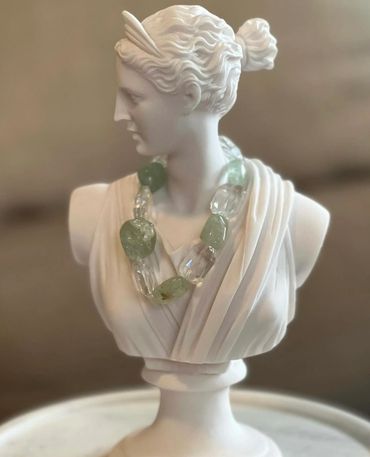 White marble bust adorned with a chunky green and clear necklace.