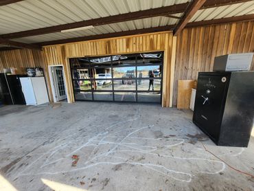 Garage interior with reflective glass garage door and wooden walls.