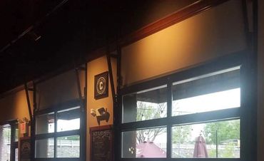 Dimly lit restaurant interior with large windows and chalkboard menus.