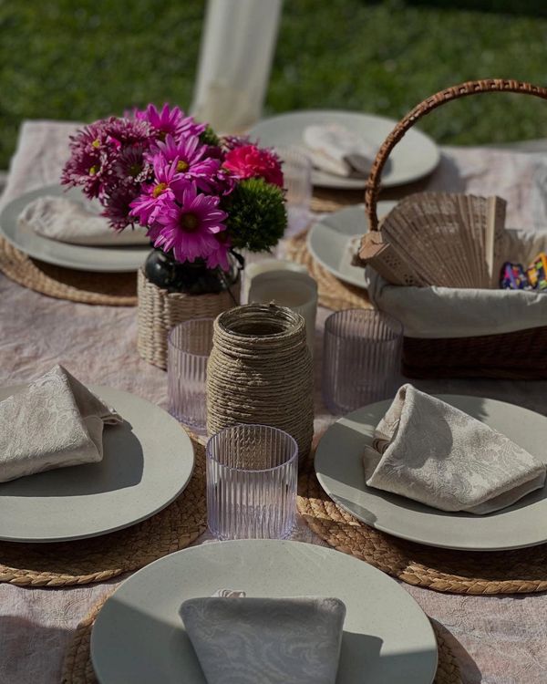 Elegant outdoor table setting with pink flowers and woven accents.
