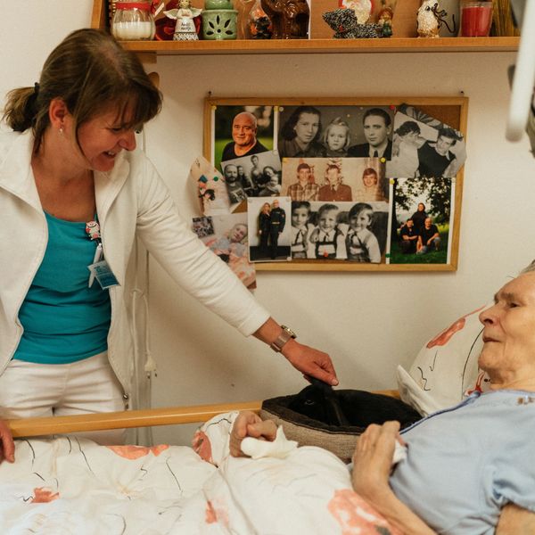 Caregiver smiling at an elderly bedridden woman she's caring for