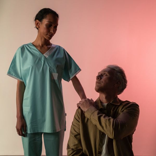 Nurse reassures elderly man with a comforting touch.