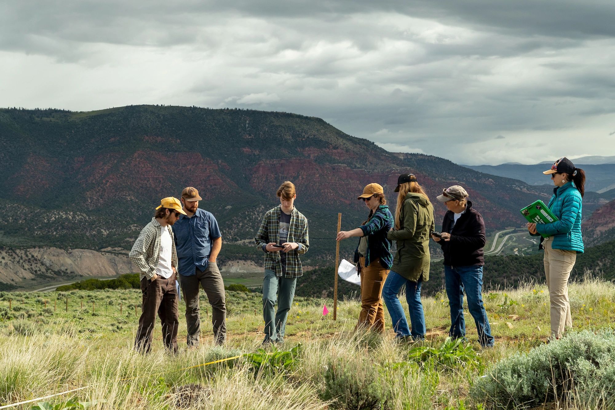 A group of people outdoors in mountainous terrain under cloudy skies.