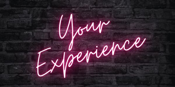 Neon sign saying 'Your Experience' on a brick wall.
