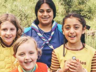 Group of smiling girls outdoors in scout uniforms.