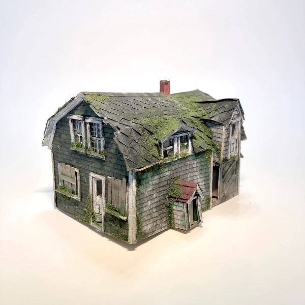 A miniature model of an old, moss-covered house with weathered shingles.