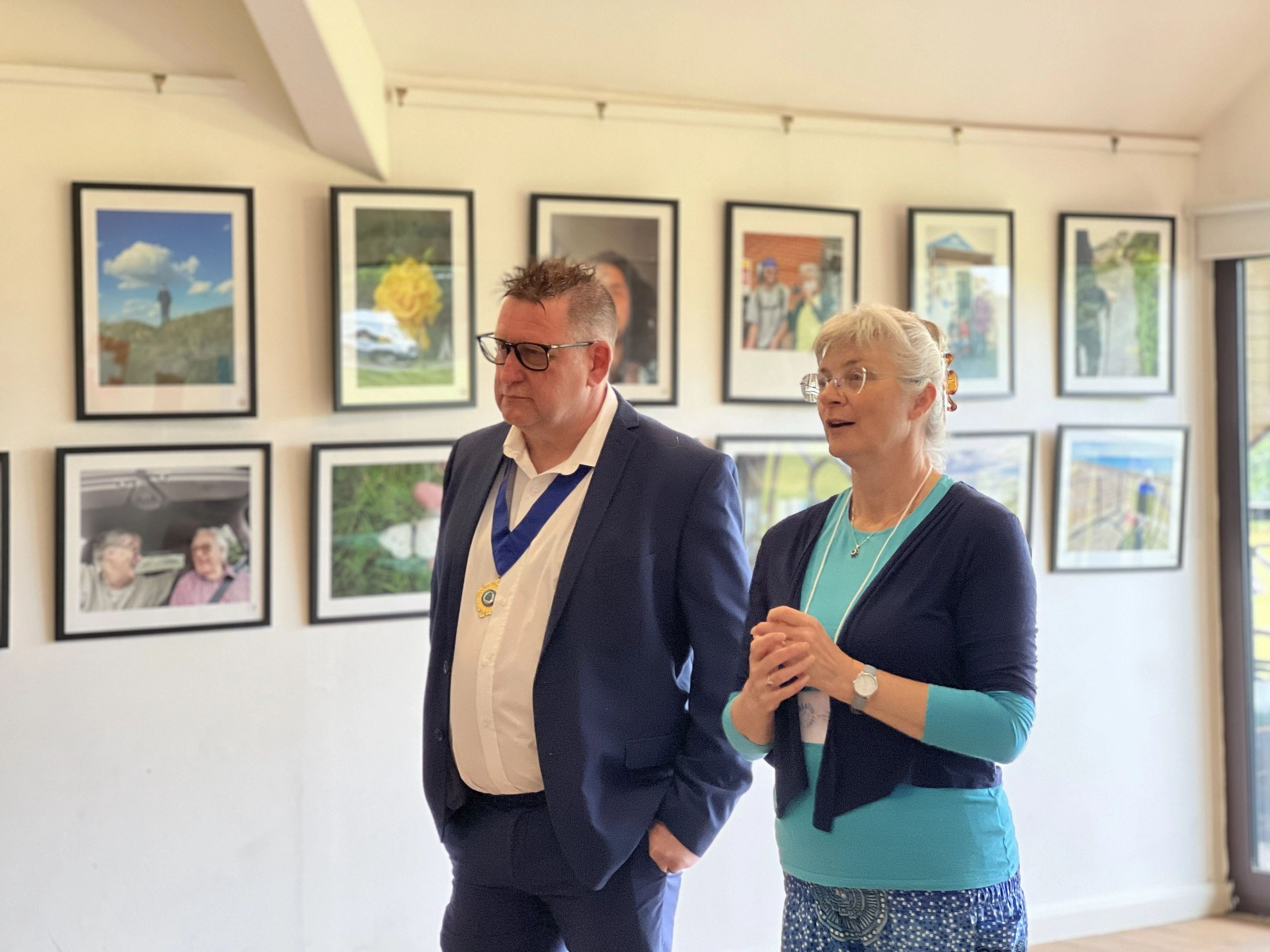 Teri and Deputy Mayor of Uckfield walking in front of hanging pictures