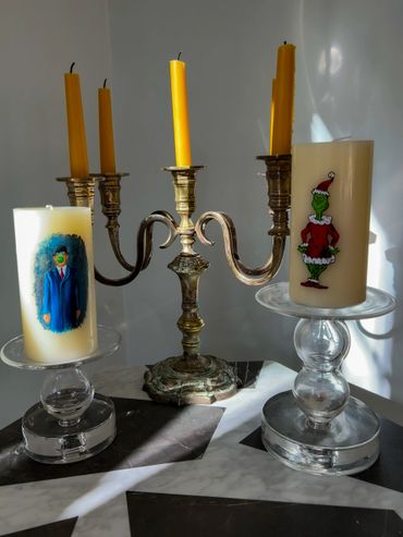 Decorative candles and a silver candelabra on a marble table with natural light.