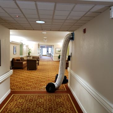 A hallway with seating and a large ventilation duct extending from the wall.
