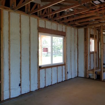 Interior of a house under construction with insulation and exposed wooden framing.