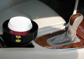 Cup holder in a car with a insert holding a cup of coffee securely. The KAZeKUP® Ultimate Cup Holder insert catches spills and drips.
