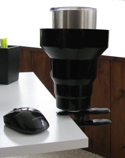 Cup Holder clipped on desk. Clip on Cup Holder holds drinks securely and out of the way. Clip the KAZeKUP Cup Holder in your work station, studio, shop and more 