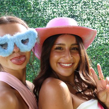 Two women posing with playful accessories outdoors.