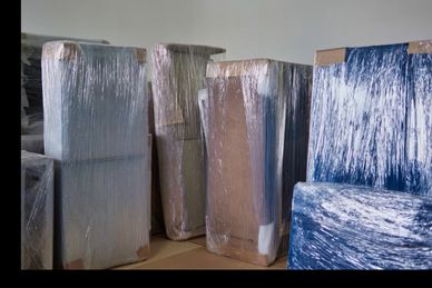 Furniture pieces wrapped in protective plastic for moving or storage.