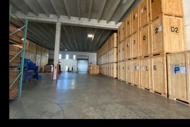 Spacious warehouse with neatly stacked wooden crates and concrete flooring.
