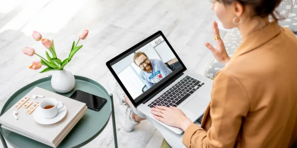 Two people engaged in a video conference call through a laptop.