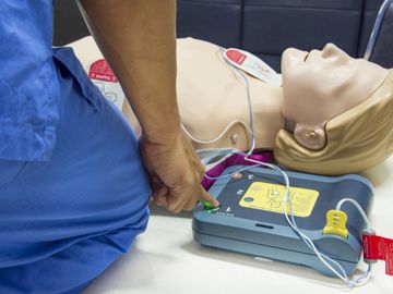 Someone performing CPR with an AED machine