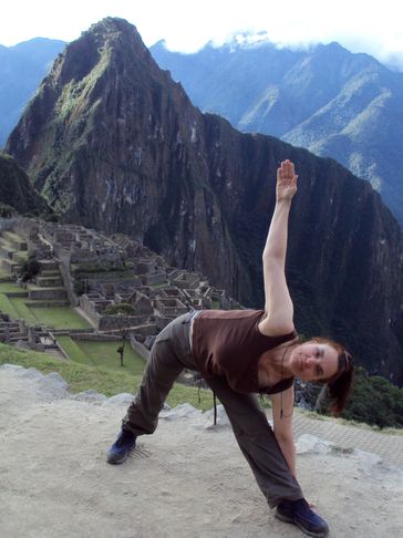 Women in a yoga pose with a view of Machu Picchu in the background.