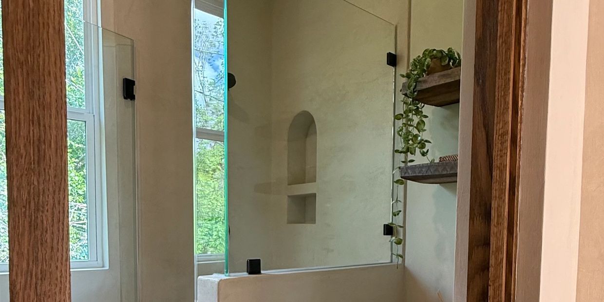 Modern bathroom with glass shower enclosure and wooden accents.