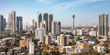 City skyline with modern skyscrapers and a tall tower under a clear sky.