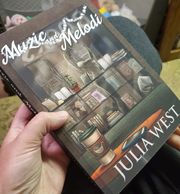 Julia West holding her first novel Muzic and Melodi for the first time.