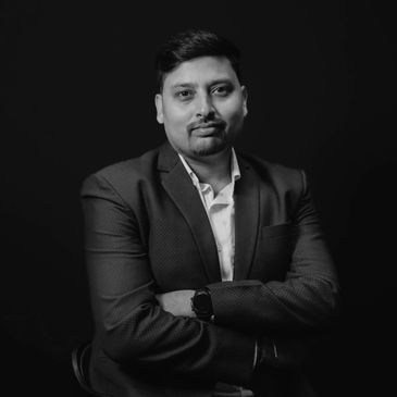 Portrait of a confident man in a blue suit against a black background.