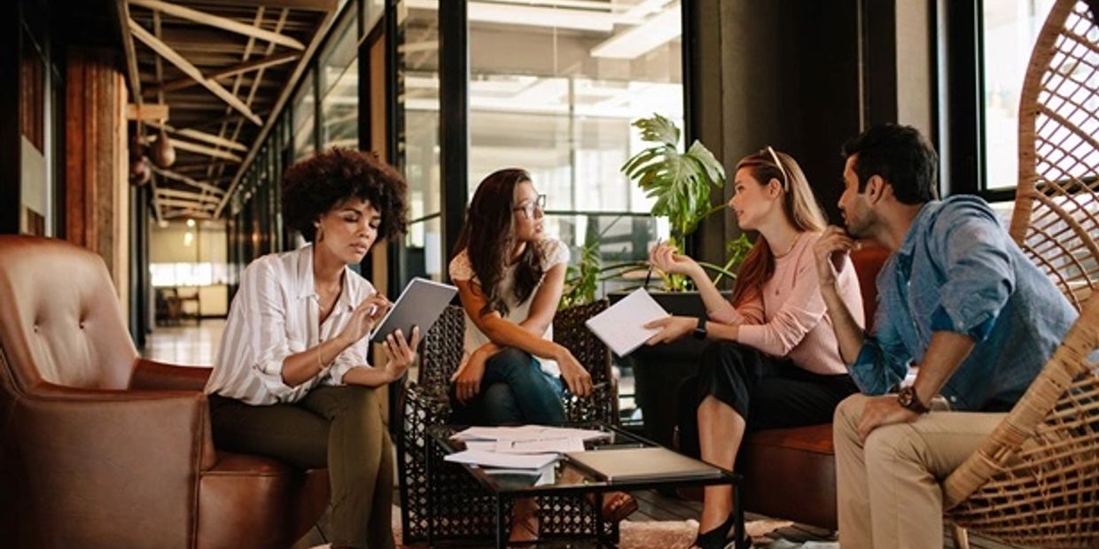 Four professionals having a discussion in an office lounge.