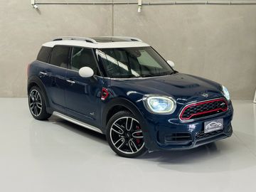 Dark blue Mini Cooper Countryman with white roof and stylish wheels in a showroom.