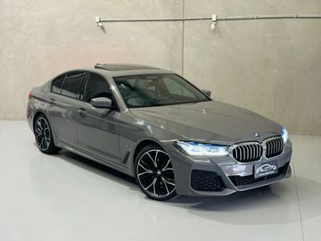 Sleek gray BMW sedan with modern design and illuminated headlights in a minimalist showroom.
