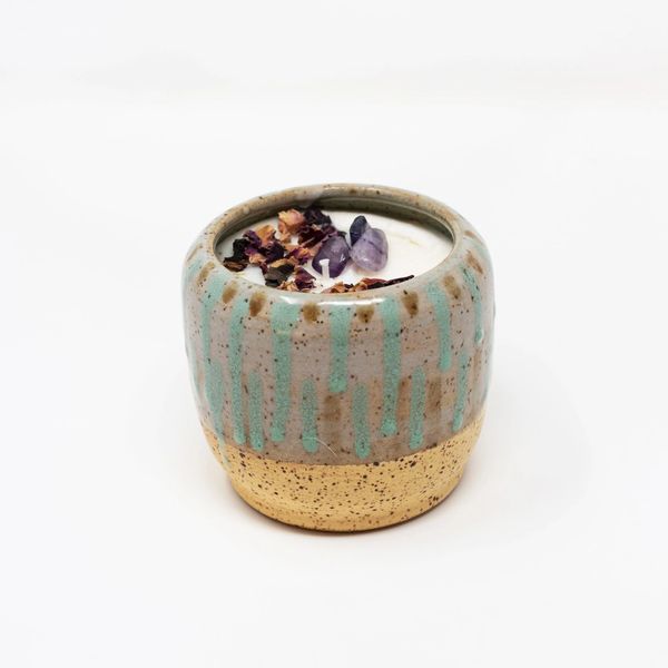 A candle in a ceramic bowl with flowers inside.