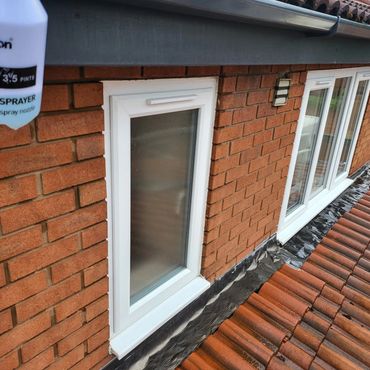 Red brick house exterior with white-framed windows and tiled roof.