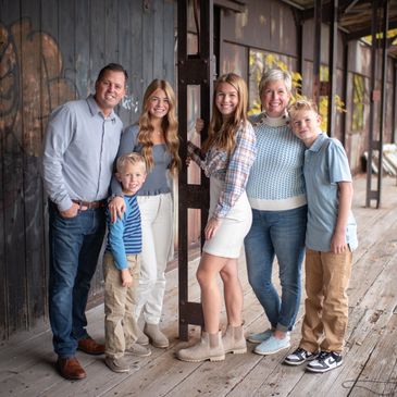 Smiling family posing on rustic wooden porch.