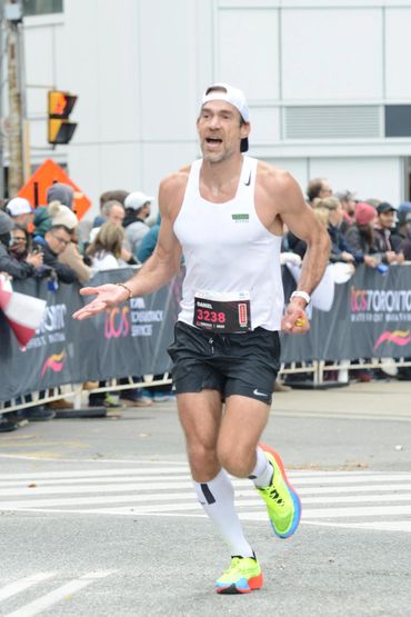 Runner celebrating with arms raised while finishing the Toronto Waterfront Marathon.
