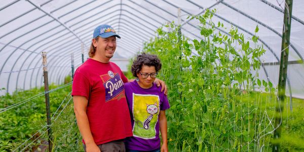 couple in hoop house with produce