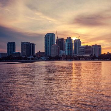 Sunset over a city skyline reflecting on calm waters.