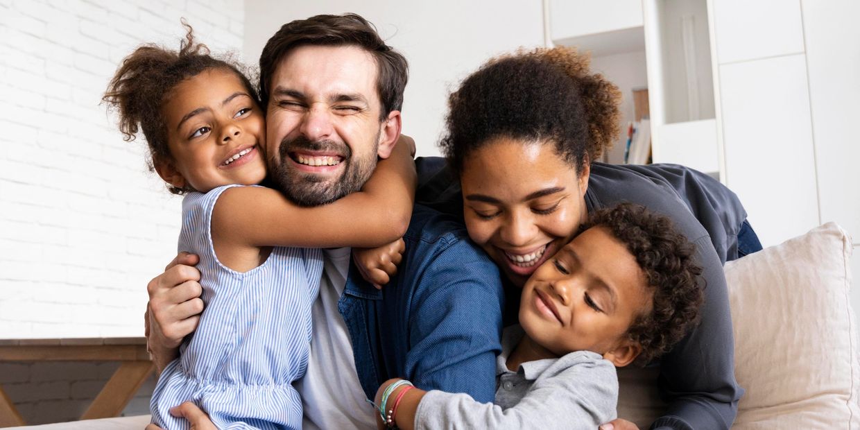 A joyful family sharing a warm group hug on a couch.