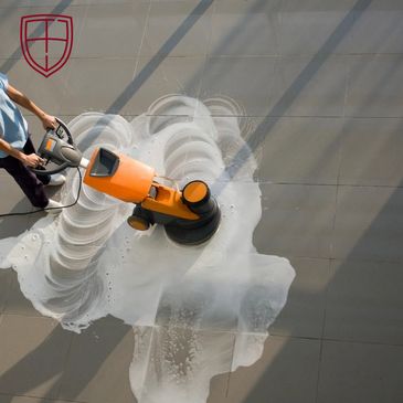 A woman uses a floor scrubber to clean tiled flooring with soap.