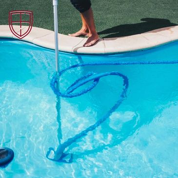 Person cleaning a pool with a vacuum tool creating bubbles.