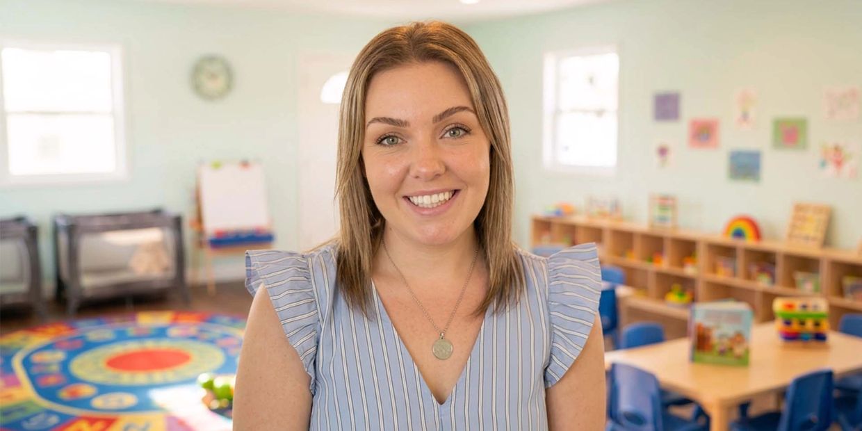 Smiling woman in a colorful classroom setting.