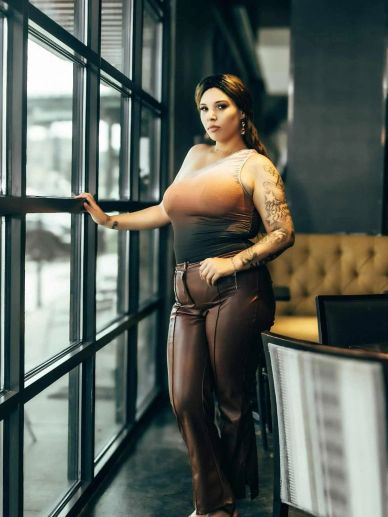 Woman standing by a large window in a stylish indoor setting.