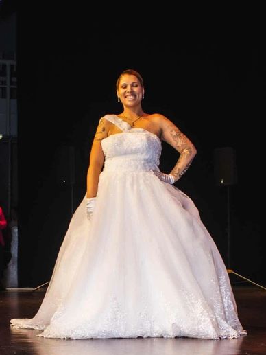 Smiling woman in a white wedding dress on stage.