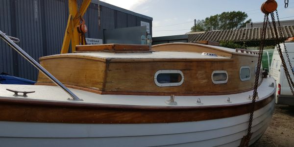 Wooden cabin cruiser boat docked near a warehouse.