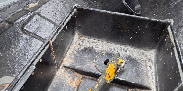 A handheld power tool inside a large black container.