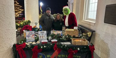 Three people at a festive outdoor holiday table with Christmas decorations and treats.