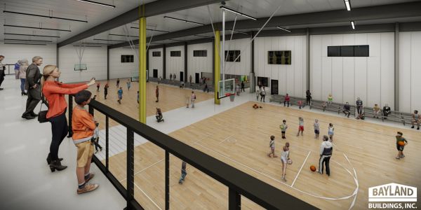Indoor basketball court with children playing and adults watching.