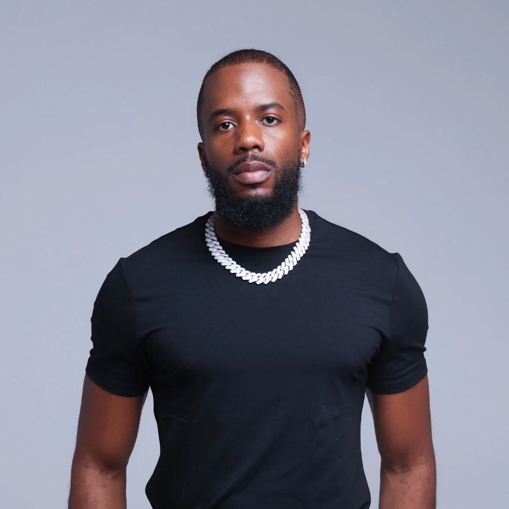 Man with a beard wearing a black shirt and silver chain necklace.