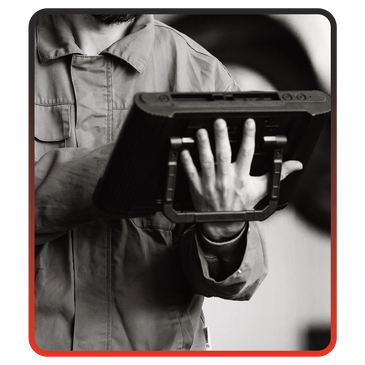 Person holding a rugged tablet with a hand strap, dressed in a work uniform.