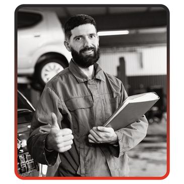 Mechanic giving thumbs up in a garage with clipboard in hand.